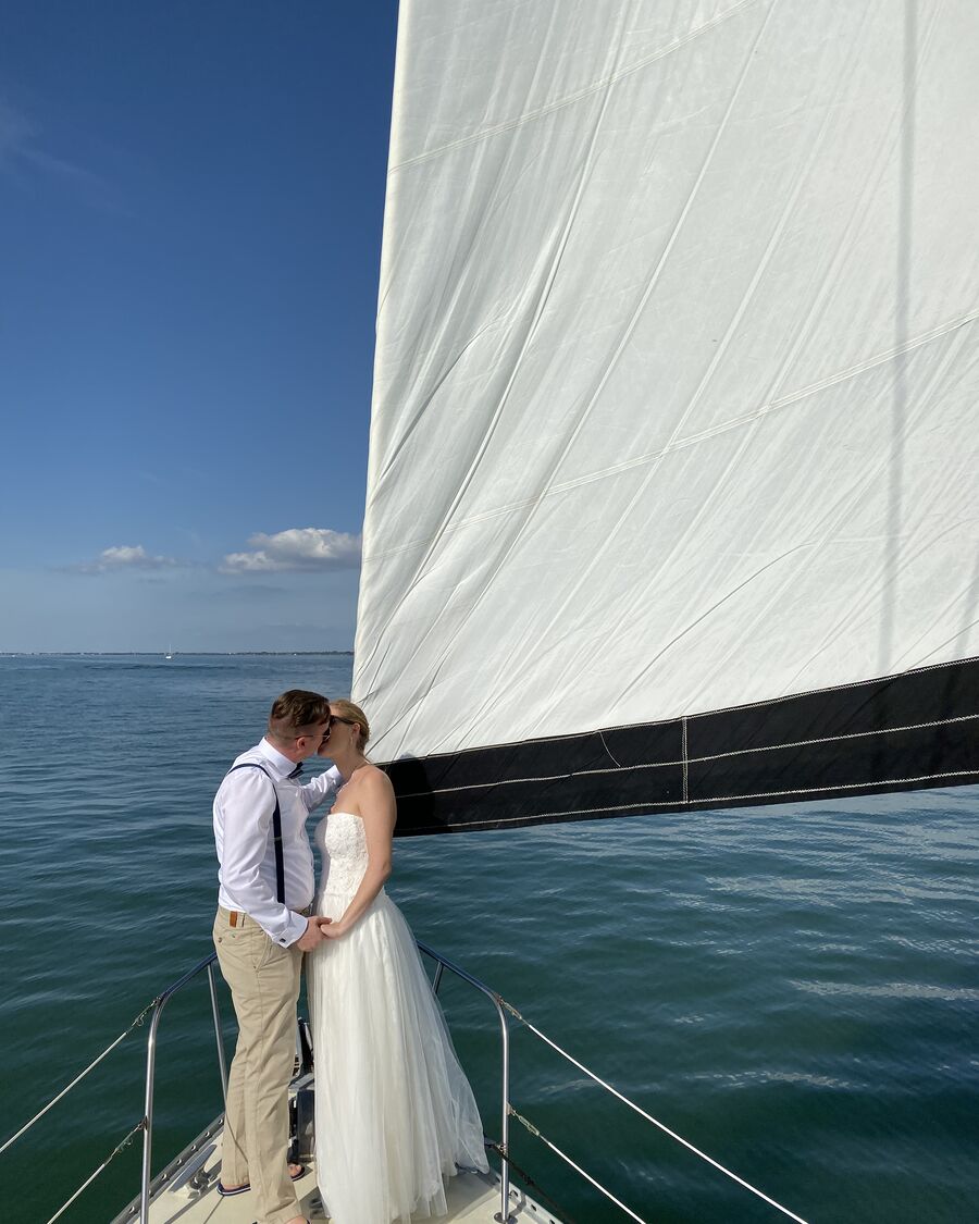 A couple on the bow of the Key Breeze under full sail on an afternoon cruise