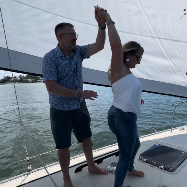 A couple dancing on the bow under the sail