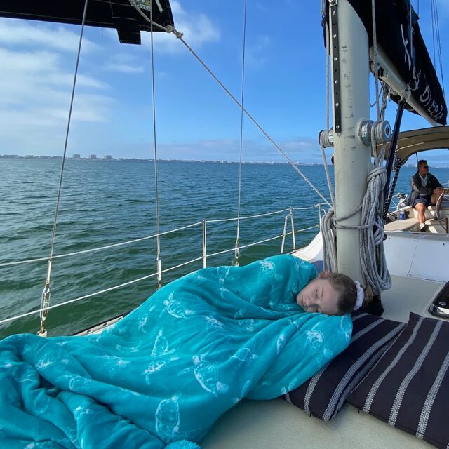A young guest asleep on deck under a turquoise blanket
